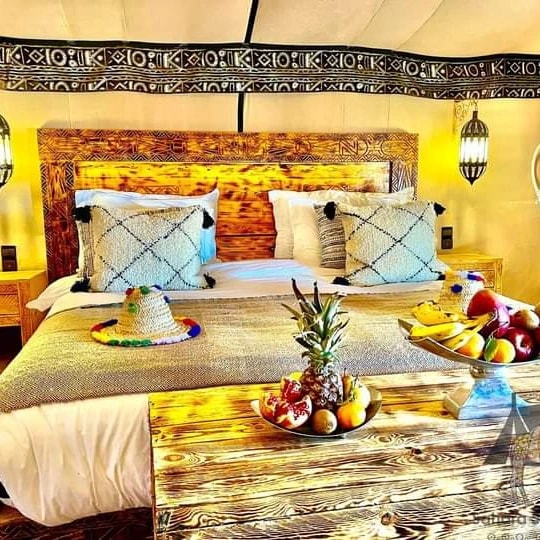 private luxury tent at a Merzouga desert camp beside the Erg Chebbi dunes at sunset